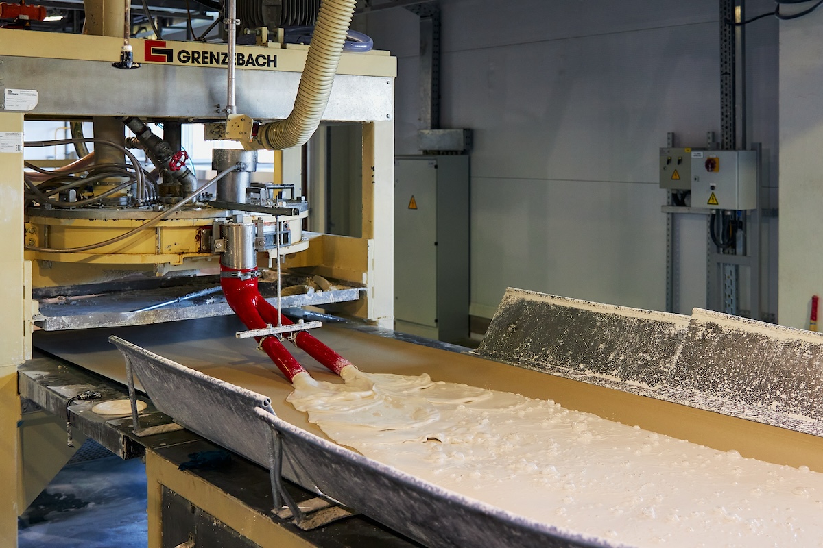 Gypsum slurry is applied to paper backing in a drywall manufacturing facility.